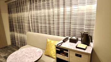 Une chambre d’hôtel équipée d’un canapé, d’une petite table ronde, d’une machine à café, d’un téléphone et d’une boîte de mouchoirs.