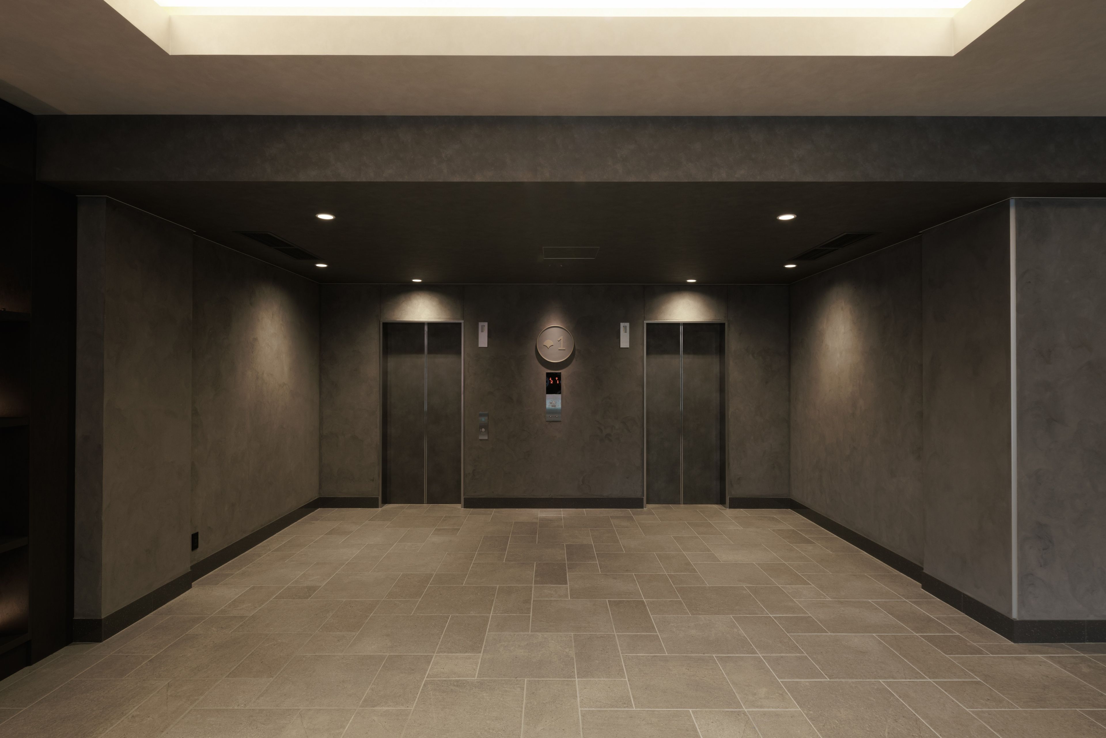 A modern elevator area with two elevators, a digital display, and a tiled floor.