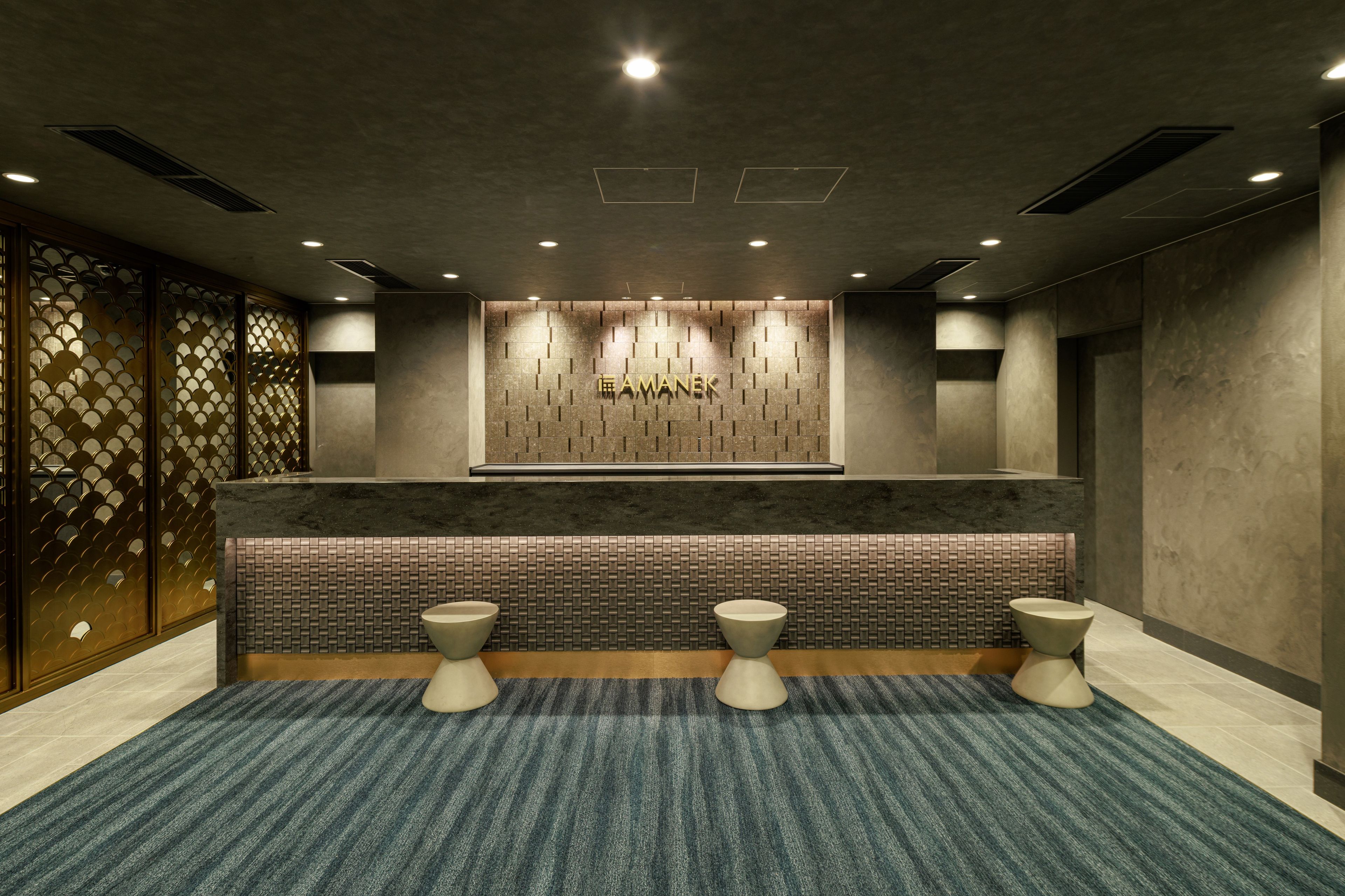 A modern reception area with a reception desk, two toilets, and a patterned wall.