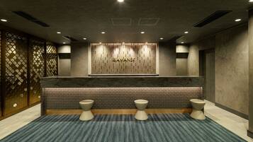 A modern reception area with a reception desk, two toilets, and a patterned wall.