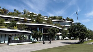 A modern building with a curved facade, a sign for 'SAKURA MACHIK,' and a pedestrian walkway. - HOTEL AMANEK Kumamoto (Kumamoto)