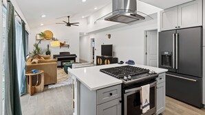 Cozinha moderna com ilha central, forno embutido e grande frigorífico.