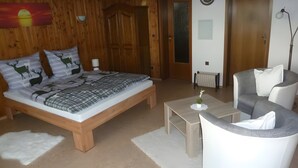 A bedroom with a wooden bed, a nightstand, a bedside table, a chair, and a radiator. - Holiday Apartment for 2 People (35 m²) in Weilheim (Baden-Württemberg) (Weilheim)