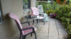 Eine Terrasse mit zwei Stühlen, einem kleinen Tisch und einem Blumentopf.