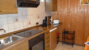 Eine Küche mit einer Edelstahlspüle, einer schwarzen Dunstabzugshaube, einem Toaster und einem kleinen schwarzen Wagen.
