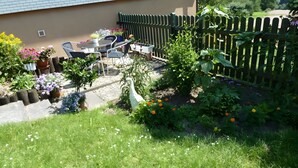 A garden with a table and chairs, a white bird sculpture, and a wooden fence. - Holiday Apartment for 2 People (35 m²) in Weilheim (Baden-Württemberg) (Weilheim)