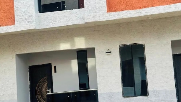 En byggnad med flera våningar, en vit och orange fasad, stora fönster och en tydligt synlig dörr med en cirkelformad design.