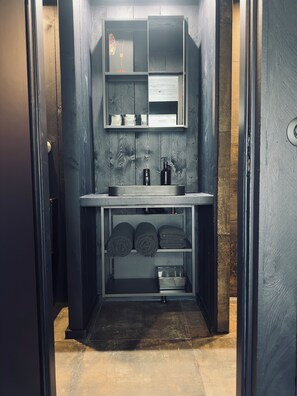 A compact, modern bathroom with a built-in sink, mirror, and storage shelves. - The Black Loft Experience (Cierp-Gaud)