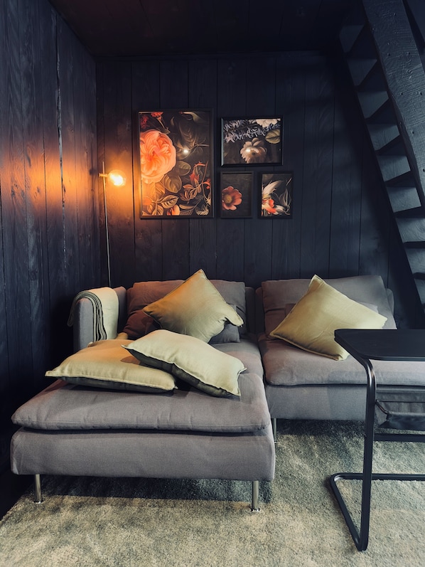 A modern living room with a sectional sofa, multiple cushions, a floor lamp, and artwork on the wall.