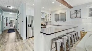 A modern kitchen with a central island, bar stools, and a dining area.
