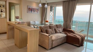 Een moderne woonkamer met een bank, een eethoek en uitzicht op zee.
