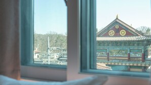 A traditional building with a tiled roof and intricate designs, viewed through a window with a white cushion. - KIMSTEL Jongno (Seoul)