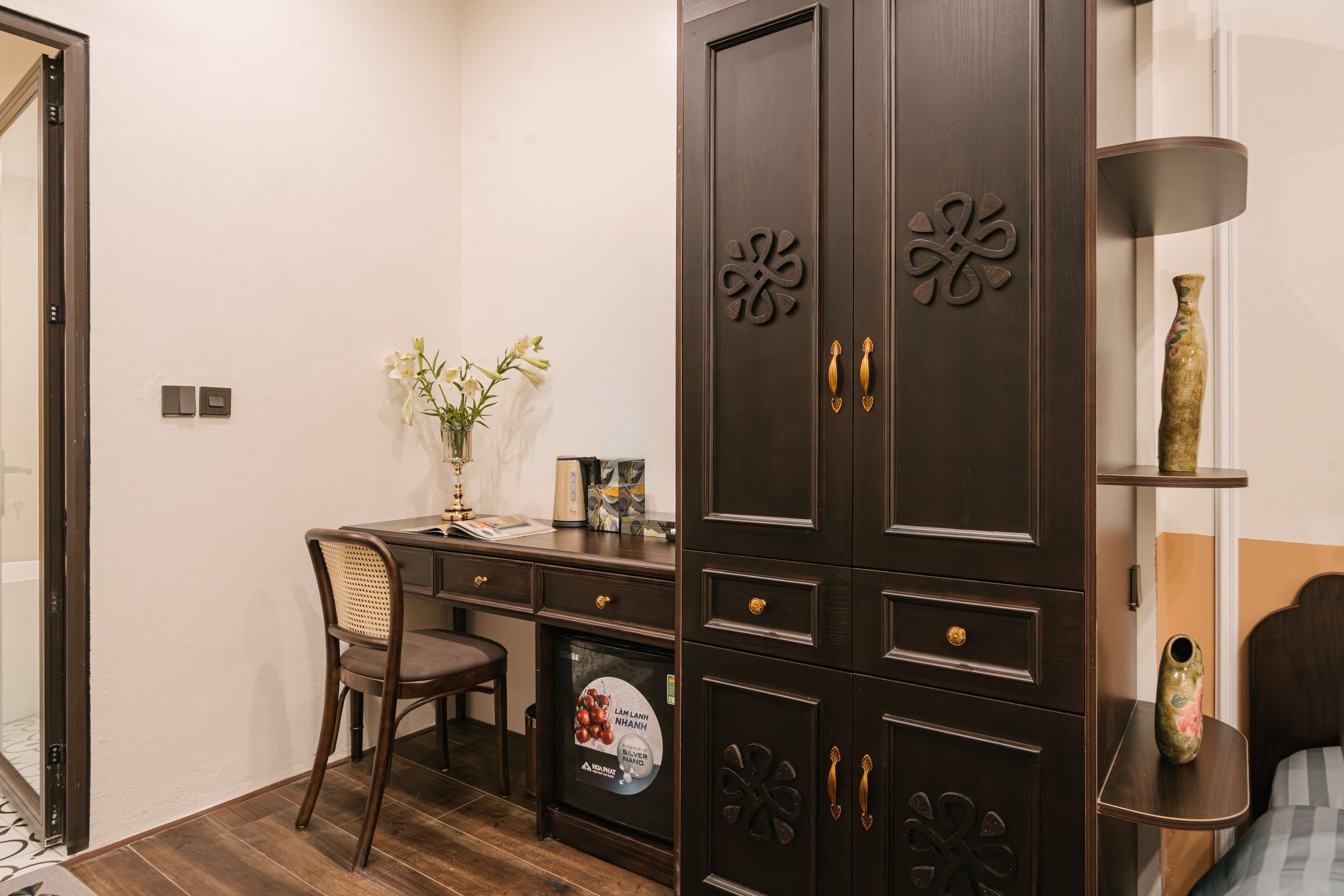 A room with a desk, chair, wardrobe, and a bed.