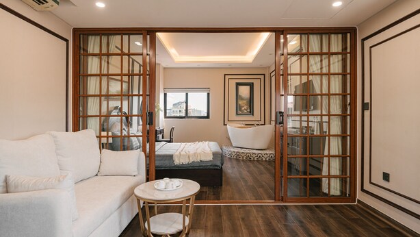 Une chambre d’hôtel avec un canapé, une table ronde, un lit, une baignoire et une vue sur la ville par la fenêtre.