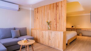 A modern room with a wooden partition, a grey sofa, a wooden bed, and a small round table with a vase. - 31 Park Hotel (Pokhara)