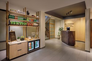 A reception area with a wooden reception desk, a shelf with snacks, and a refrigerator with beverages. - 31 Park Hotel (Pokhara)
