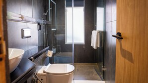 A modern bathroom with a glass shower enclosure, a toilet, and a sink. - 31 Park Hotel (Pokhara)