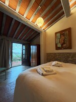 Un dormitorio con una cama grande, un cuadro en la pared y vistas a través de la puerta abierta.