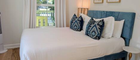 A bed with a blue headboard, white bedding, and patterned pillows.
