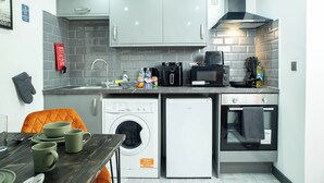 A compact kitchen with a washing machine, a microwave, and a small oven. - City Centre Studio | Fast Wi-Fi | Workspace | Washer/Dryer | Netflix | Air Fryer (Bradford)