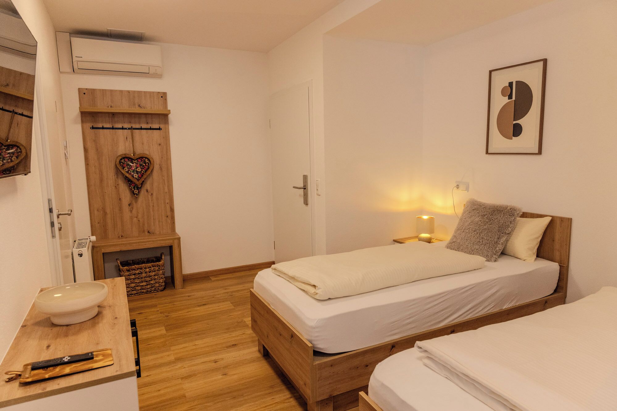 A bedroom with a wooden bed, bedside table, and a wall-mounted air conditioner.