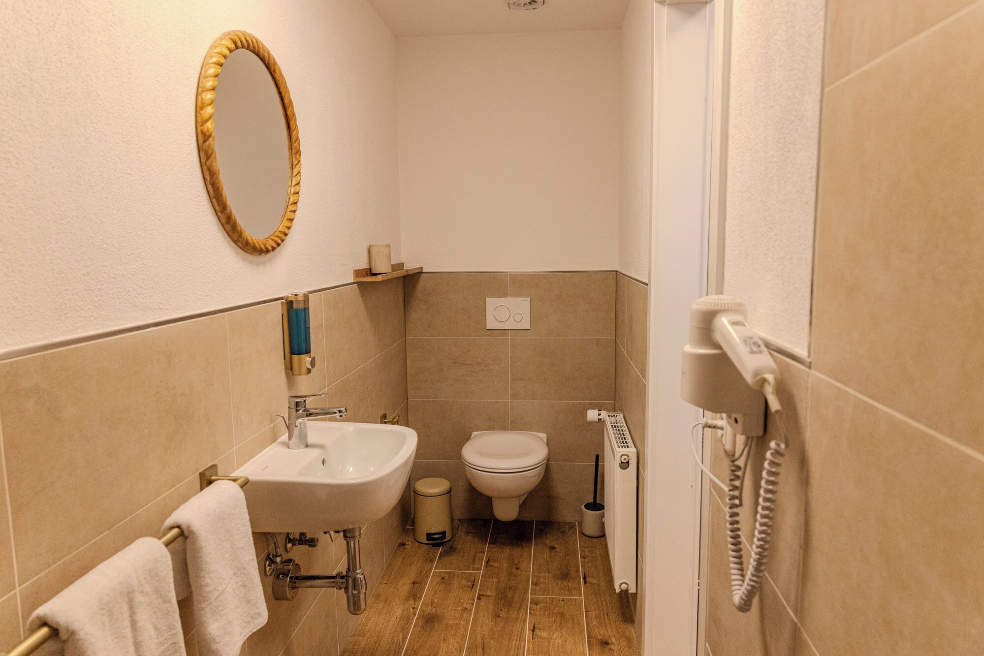A bathroom with a sink, toilet, and bidet, a towel rack, and a mirror.