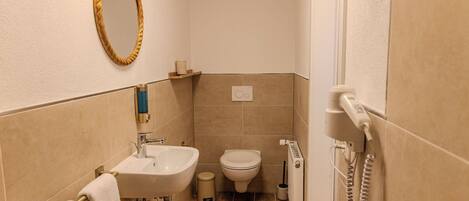 A bathroom with a sink, toilet, and bidet, a towel rack, and a mirror.
