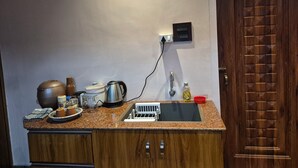 A kitchen with a sink, a kettle, a coffee pot, and a clock on the wall. - Cozy Roost, quiet place (Guwahati)