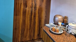 A kitchen with a wooden cabinet, a granite countertop, and various kitchen items. - Cozy Roost, quiet place (Guwahati)