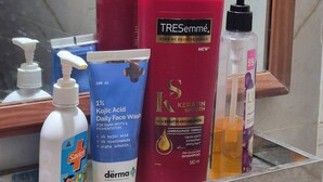 A bathroom shelf with various personal care products including a bottle of Kojic Acid Daily Face Wash, a red TRESemmé shampoo bottle, and a bottle of lotion. - Cozy Roost, quiet place (Guwahati)