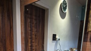 A wooden door, a clock, a kitchen area with a sink, and a rug. - Cozy Roost, quiet place (Guwahati)