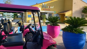 Une voiturette de golf est garée devant un bâtiment sur lequel on peut lire l’inscription « Marisol ».
