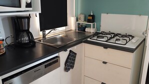 Une cuisine compacte équipée d’un four à micro-ondes, d’une machine à café, d’une cuisinière à gaz et d’un lave-vaisselle.