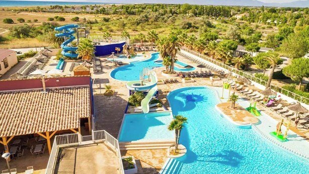 Un complexe hôtelier doté d’une grande piscine, de toboggans aquatiques et d’espaces de détente offrant une vue sur le paysage environnant.