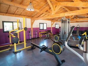 Une salle de sport équipée de matériel de musculation, de bancs et de tapis de course.