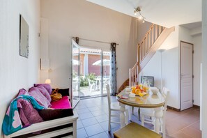 Une pièce comprenant un canapé, une table à manger avec des chaises, un escalier et une porte.