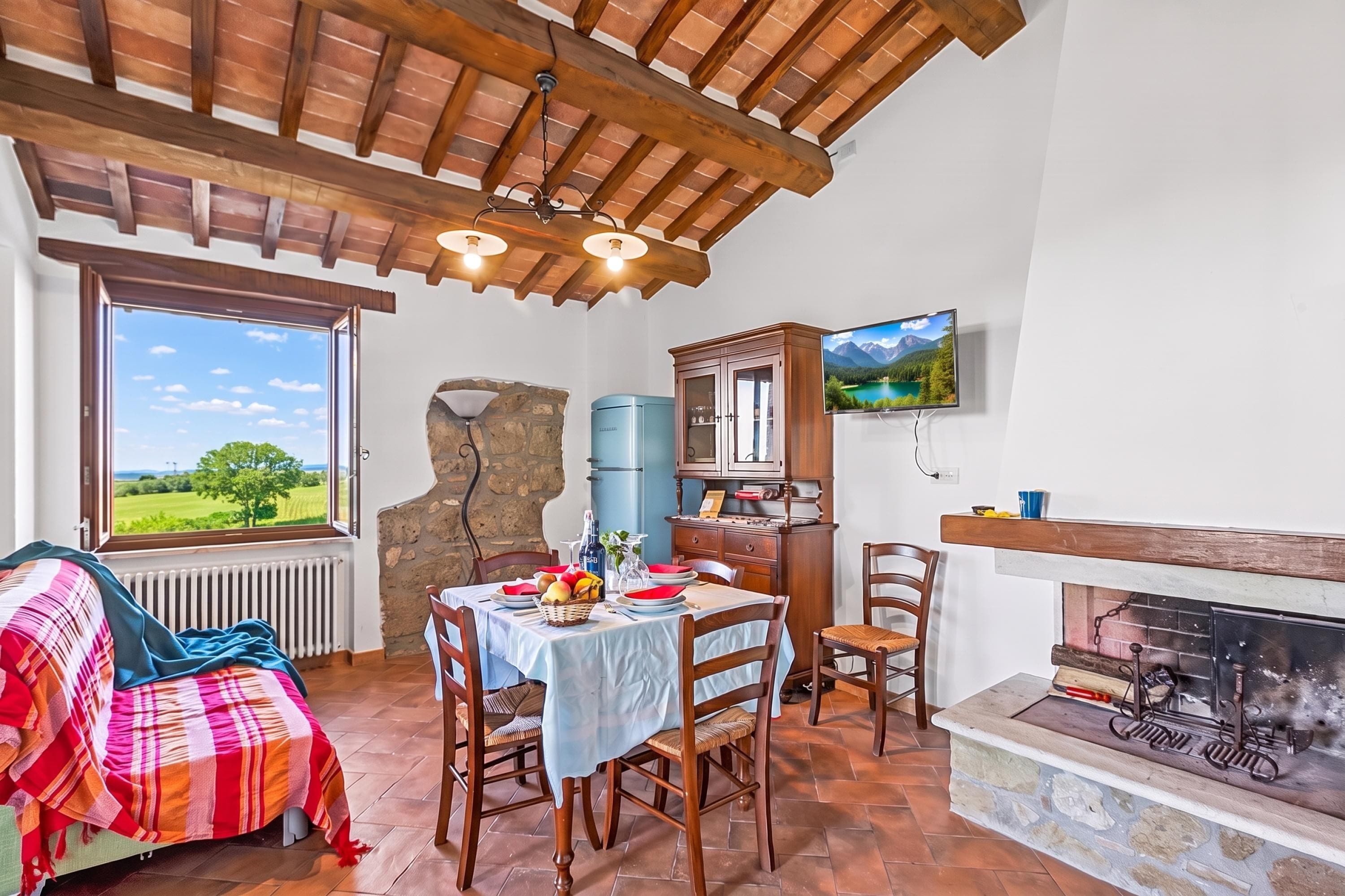 A cozy room with a dining table set for two, a fireplace, and a stone wall.
