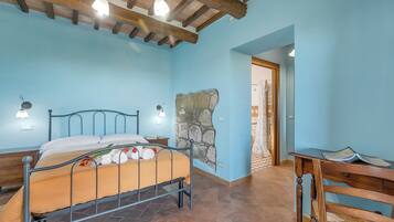 Une chambre à coucher avec un lit, un bureau, une chaise, un mur en pierre et un plafond en bois.