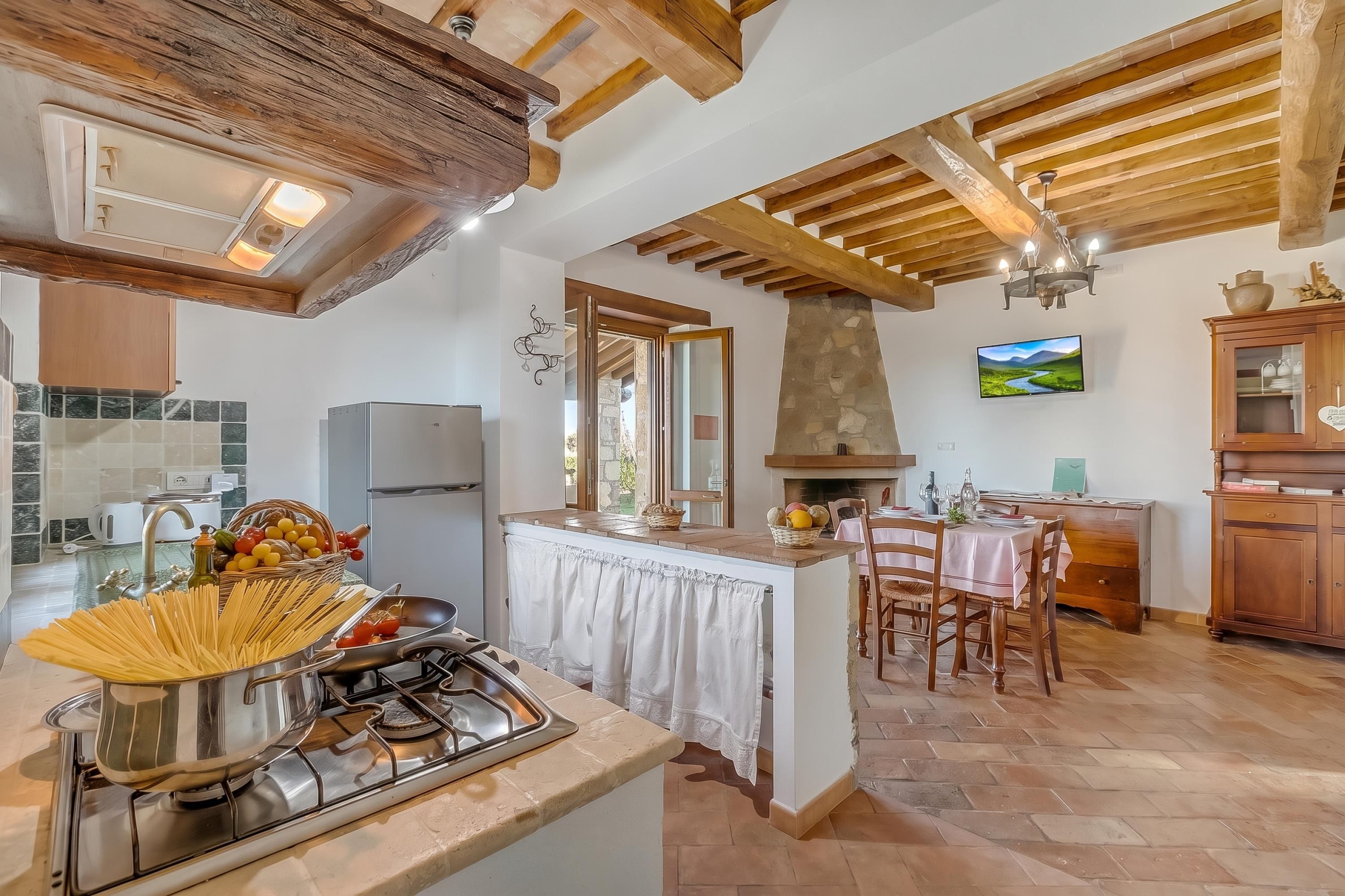 A kitchen with a gas stove, a dining area with a table and chairs, and a stone fireplace.