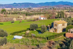 A rural landscape with a stone house, a swimming pool, and a clear view of distant mountains. - Le Sorgenti House (Pitigliano)