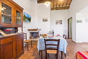 A dining area with a table set for two, a fireplace, and a wooden cabinet with glass doors.