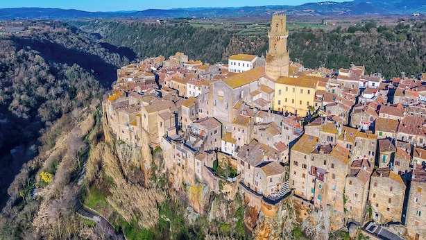 A historic town with stone buildings, a prominent tower, and a river. - Le Sorgenti House (Pitigliano)