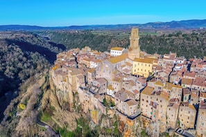 A historic town with stone buildings, a prominent tower, and a river. - Le Sorgenti House (Pitigliano)