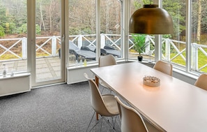 A dining area with a table, chairs, a pendant light, and a view of outdoor seating and trees. - 3 bedroom amazing home in Ringkøbing (Ringkøbing)