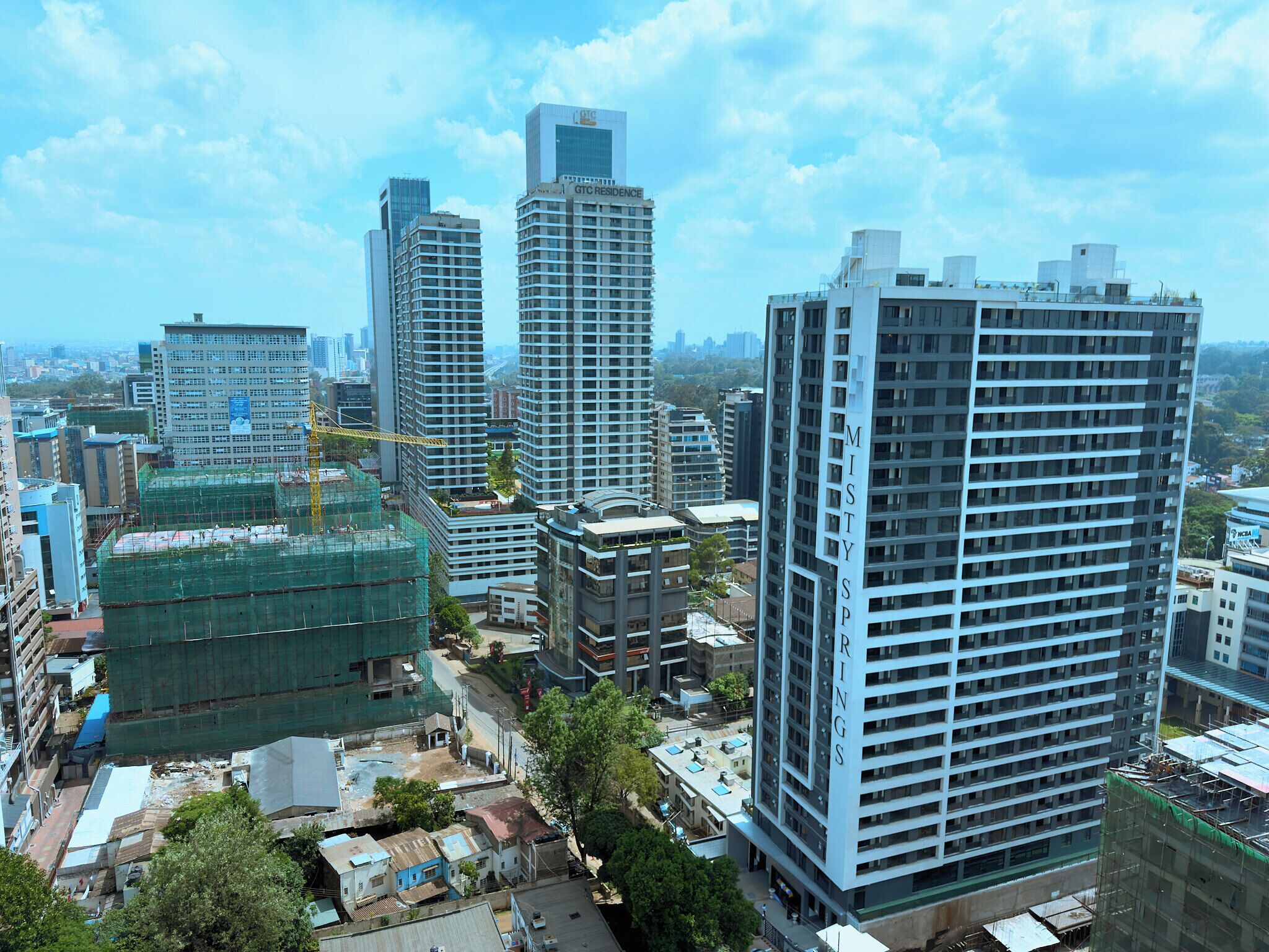 A high-rise building with multiple floors, surrounded by other buildings and greenery.