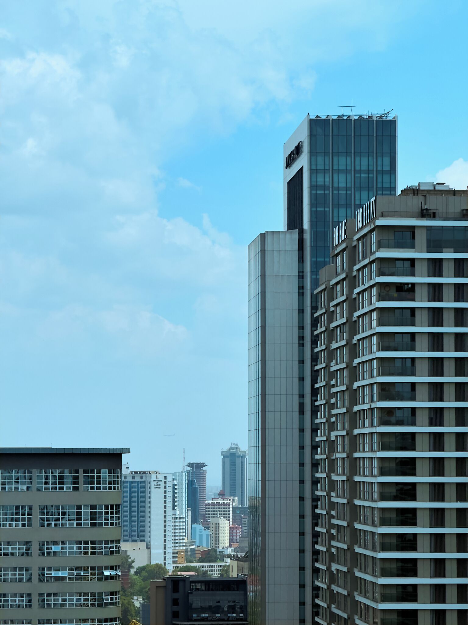 A high-rise building with a modern glass facade, surrounded by other buildings in an urban setting.
