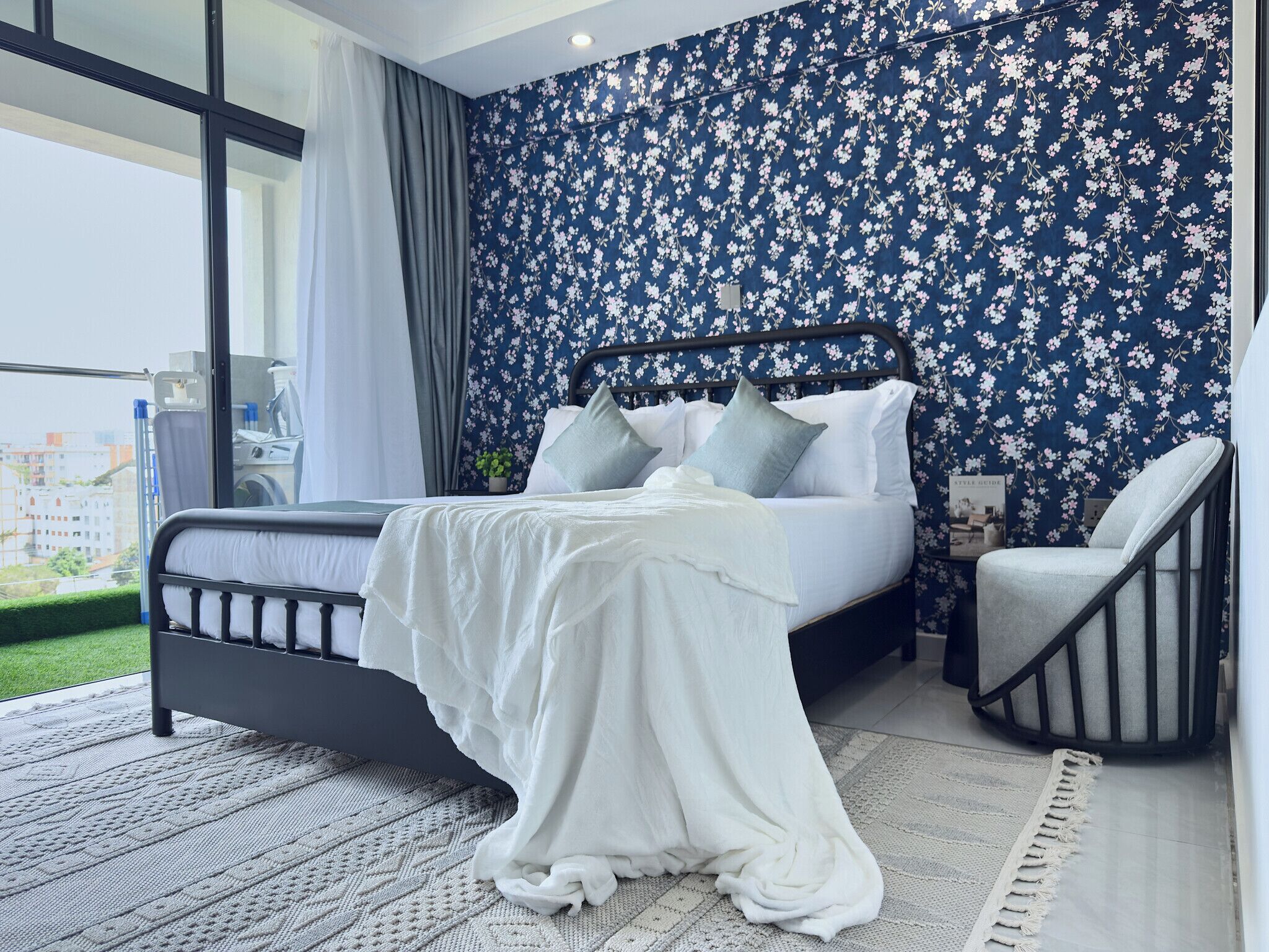 A bedroom with a bed, a chair, a window, and a balcony.