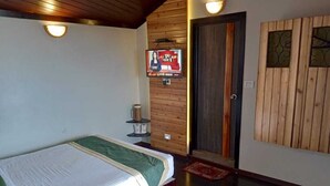 Ein Schlafzimmer mit einem Bett, Holzwandverkleidung, einer Tür und einem an der Wand befestigten Fernseher.
