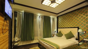 Ein Hotelzimmer mit Bett, Fernseher, Nachttisch, Lampe und einer Wand mit Muster.