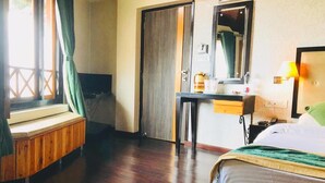 Ein Hotelzimmer mit einem Bett, einem Schreibtisch, einem Stuhl, einem Fenster mit Vorhängen und einer Tür.